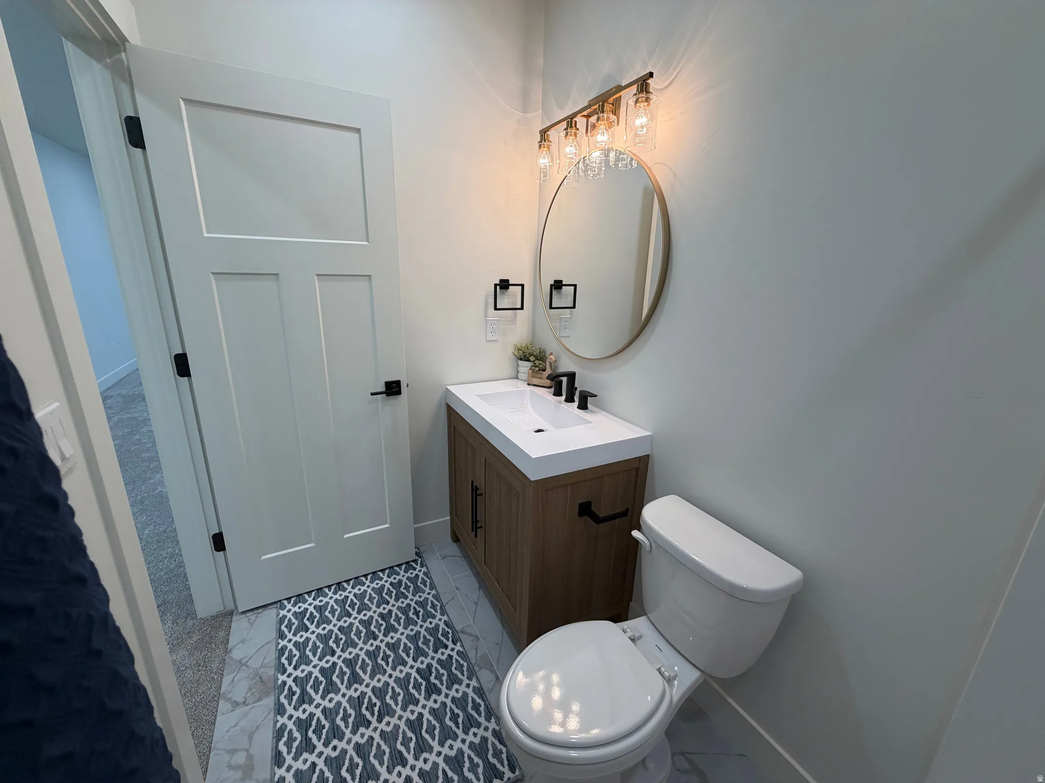Powder room featuring a single-sink vanity with wood-finish cabinetry, a white countertop, and a matte black faucet