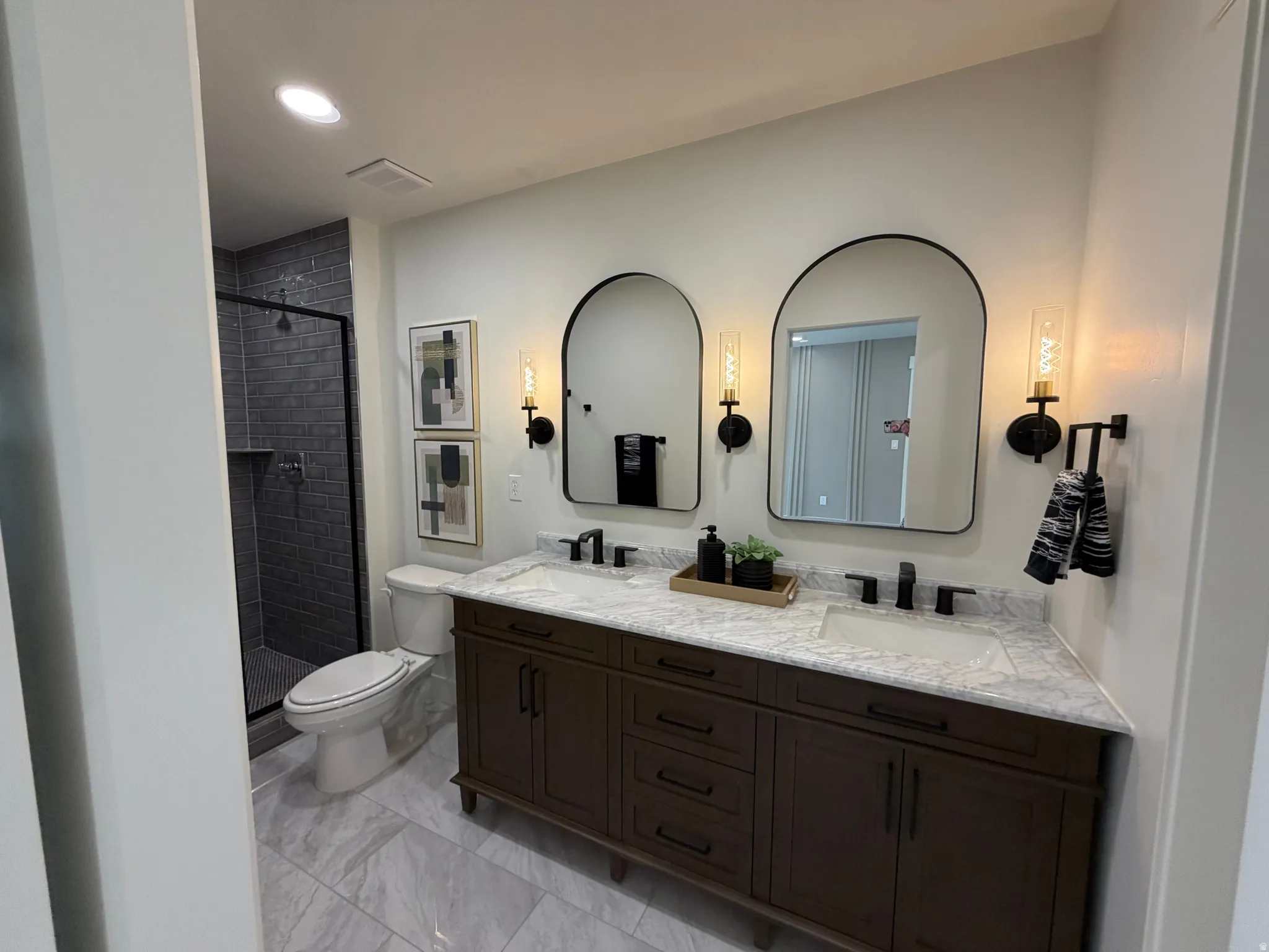 Bathroom featuring a dual vanity with a stone-finish countertop, dark wood-finish cabinetry, and matte black fixtures