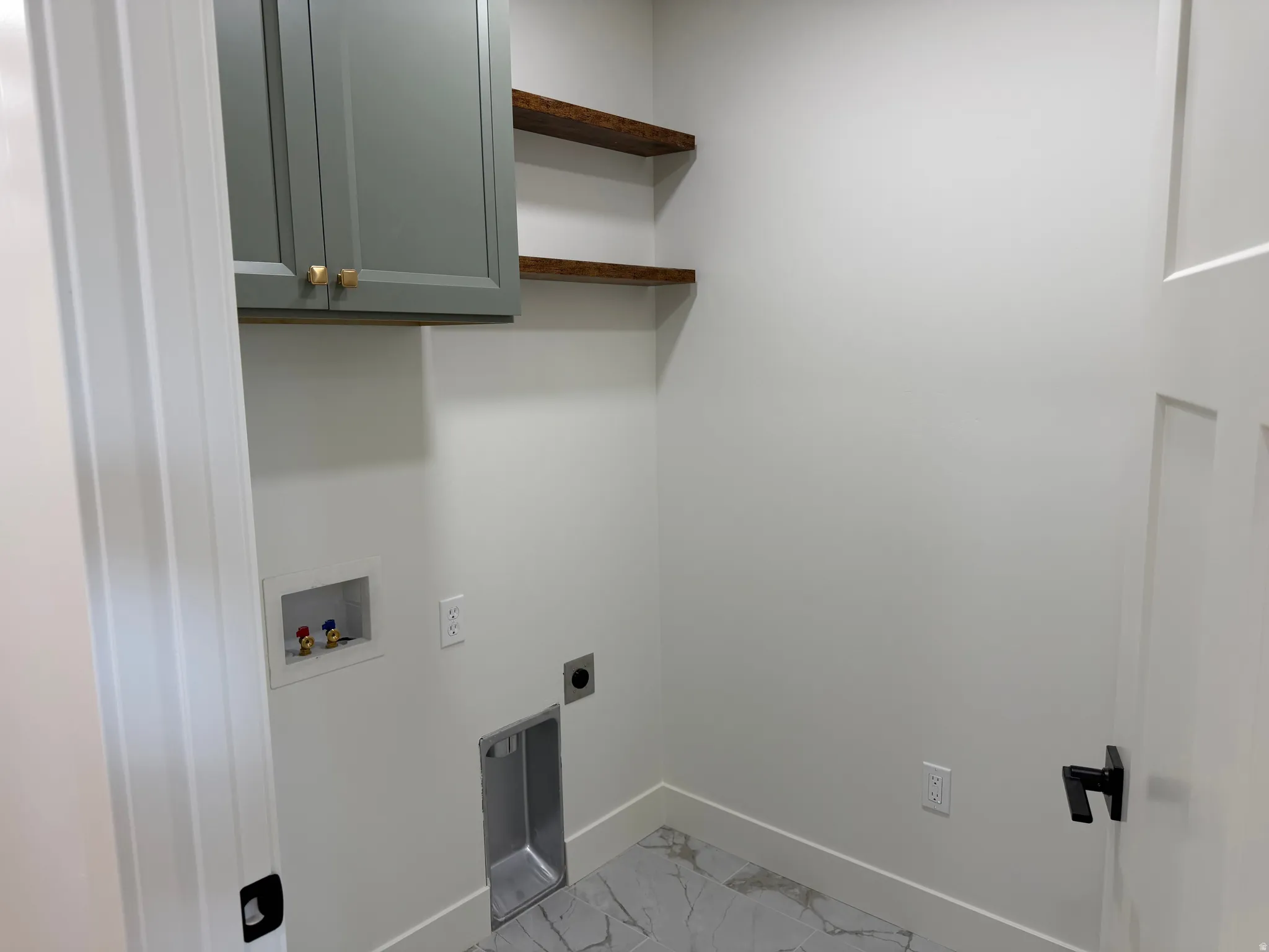 Laundry room featuring a light gray wall cabinet with gold hardware, two rustic wood floating shelves, a utility sink, and light gray marble-look flooring