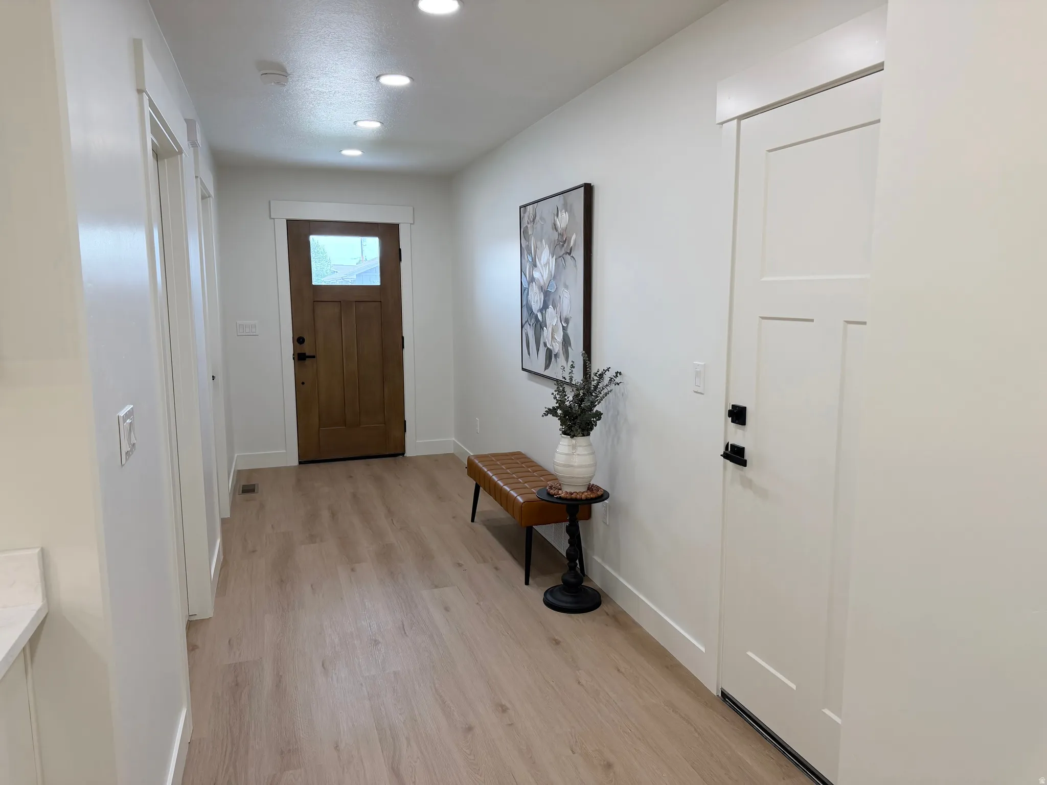 Entryway featuring light wood-finish flooring, recessed lighting, and a solid wood front door with frosted glass paneling