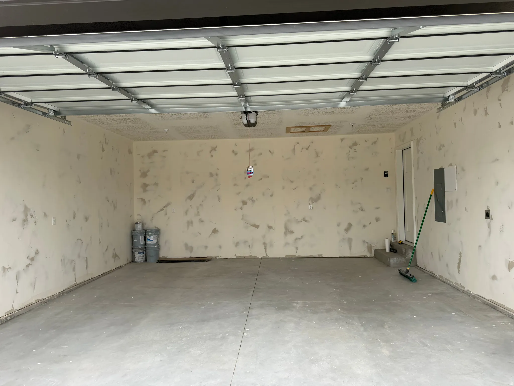 Spacious garage with concrete flooring, automatic garage door, and interior access door