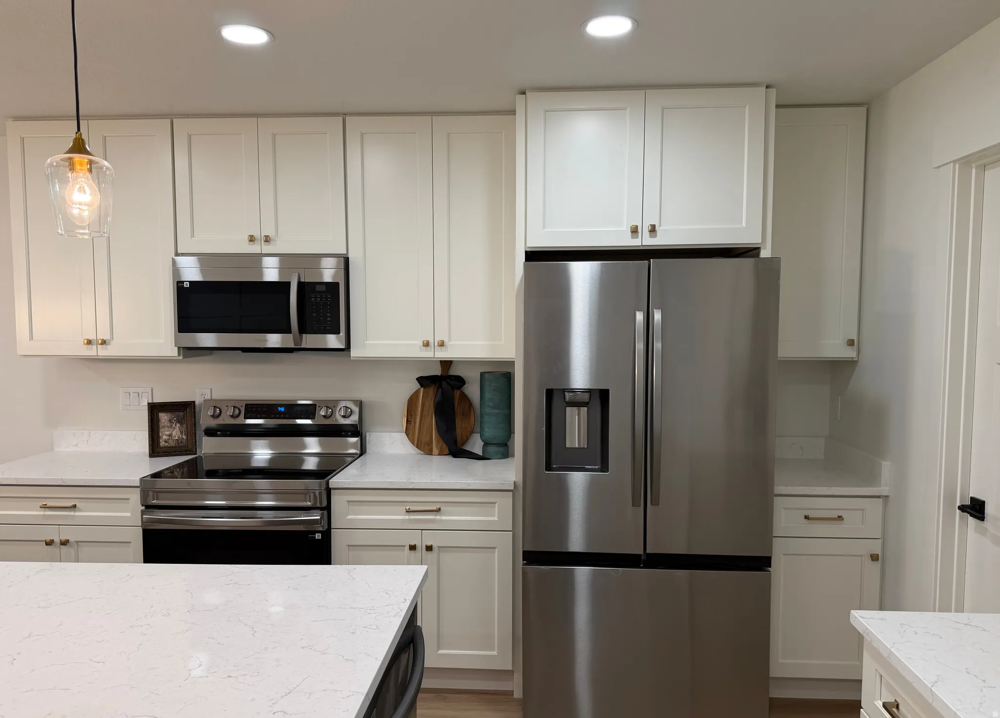 Bright kitchen showcasing white shaker cabinetry, stainless steel appliances, and light-toned countertops