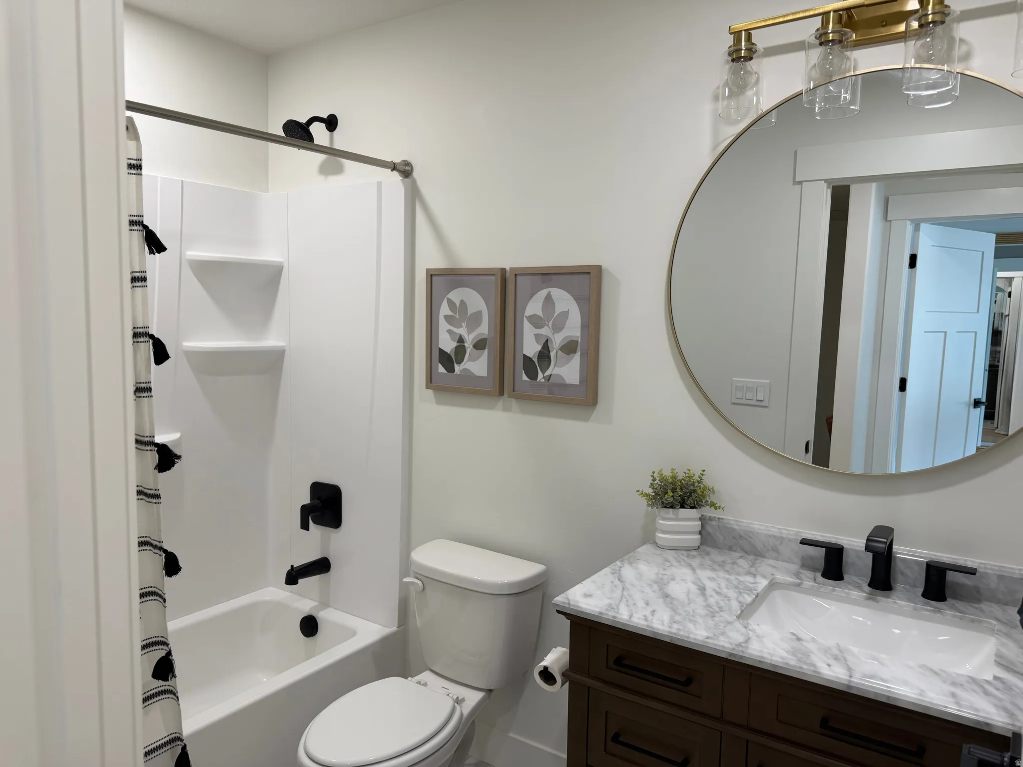 Bathroom featuring a white tub/shower combination with matte black fixtures, a contemporary toilet, and a vanity with a white stone countertop