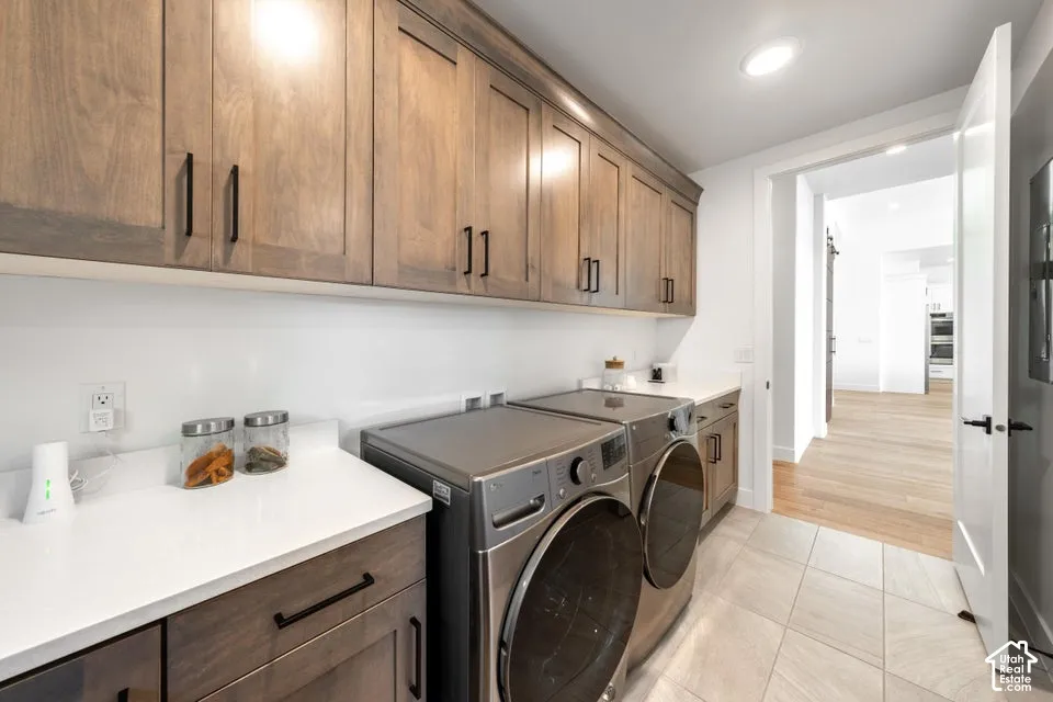 Laundry room featuring extensive wood-finish cabinetry, white countertops, and light-toned tile flooring