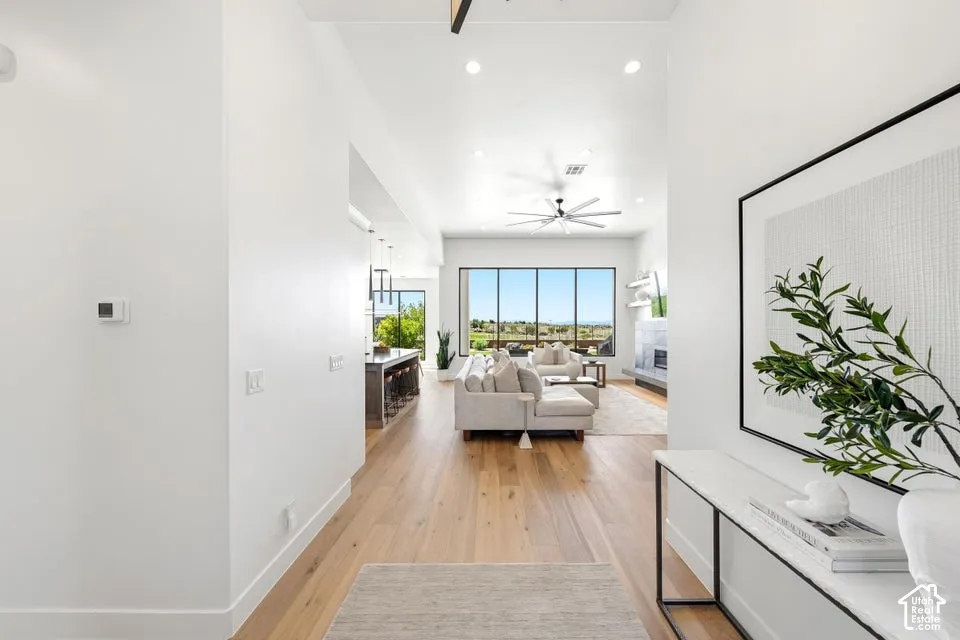 Open-concept living space with wood-finish flooring, vaulted ceilings, and a contemporary ceiling fan