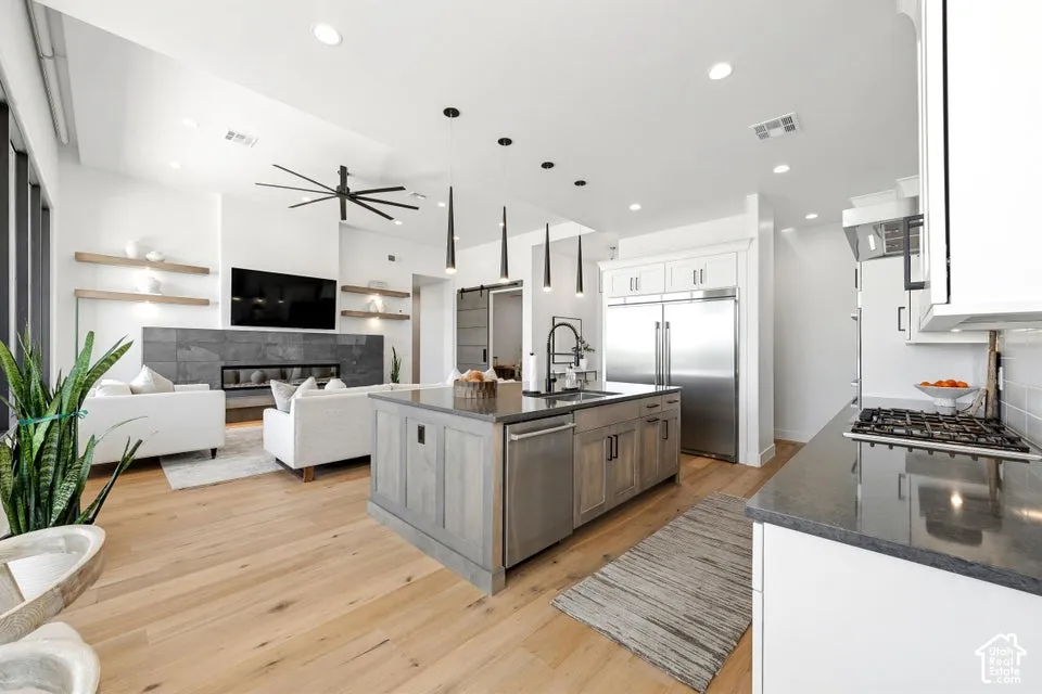 Open-concept living space featuring wood-finish flooring, a contemporary fireplace with dark stone surround, and recessed lighting