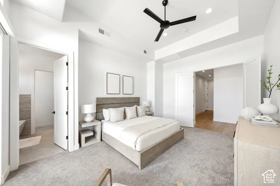 Spacious bedroom featuring plush carpeting, a modern ceiling fan, recessed lighting, and a tray ceiling