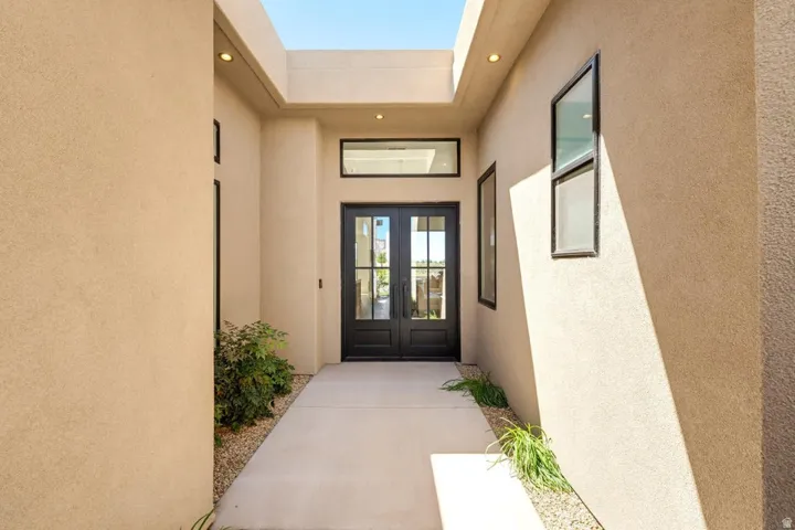 Modern stucco exterior featuring double entry doors with glass panels, a transom window, and a skylight