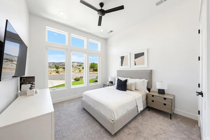 Vaulted ceiling bedroom with a prominent window wall, featuring six individual panes overlooking the exterior surroundings