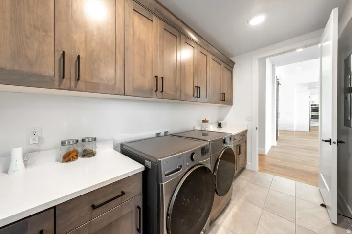 Laundry room featuring extensive wood-finish cabinetry, white countertops, and light-toned tile flooring