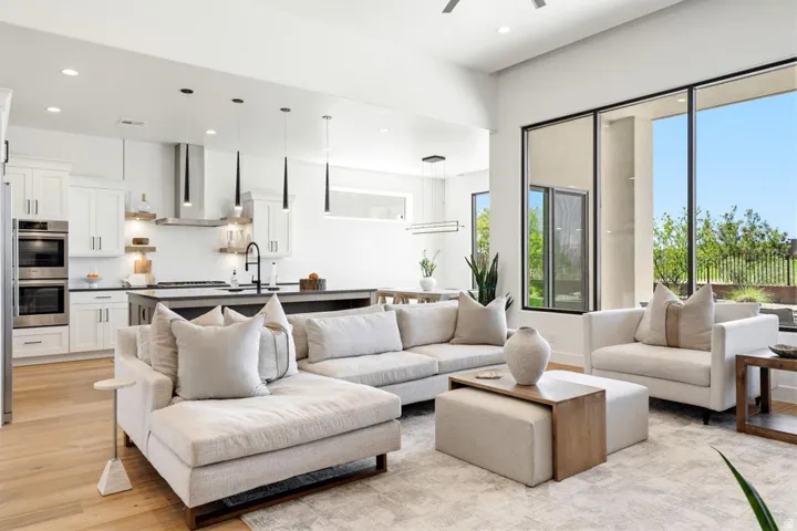 Open-concept living space featuring high ceilings, wood-finish flooring, and large format windows