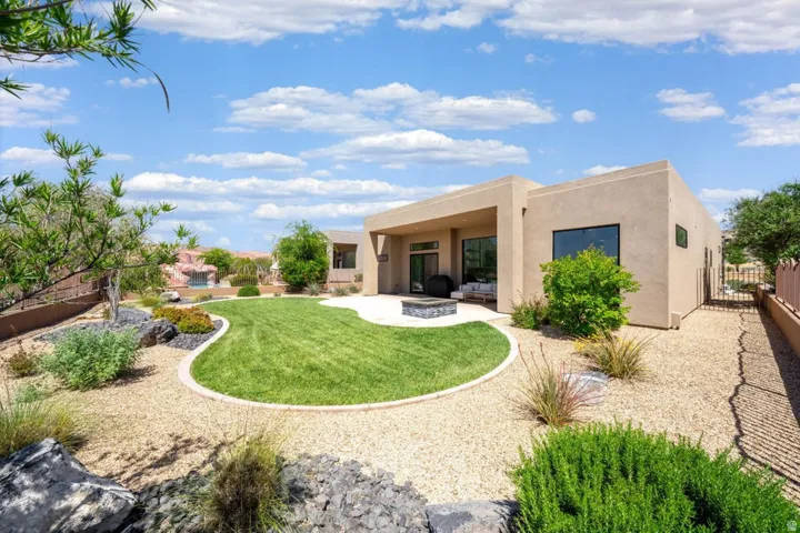 Contemporary stucco exterior with a covered patio, a manicured lawn, and a built-in fire pit