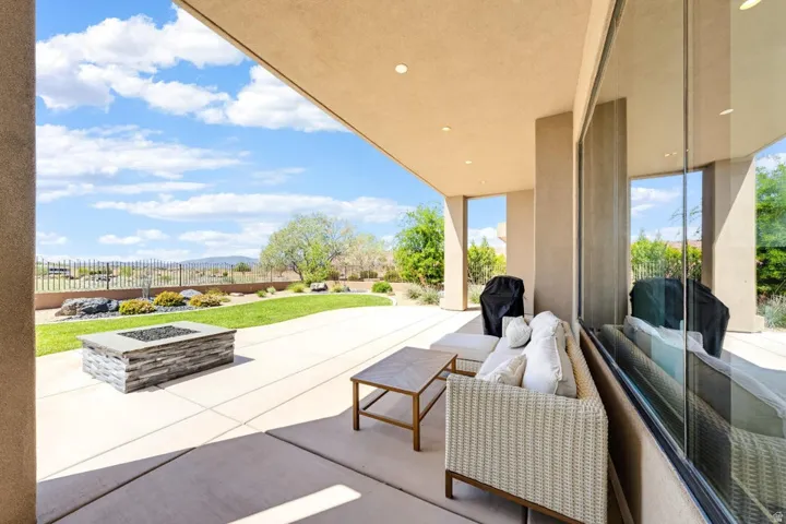 Expansive covered patio featuring a stone-clad fire pit, concrete flooring, and a manicured lawn