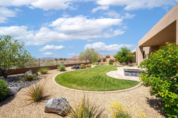 Expansive backyard featuring a curvilinear lawn, gravel ground cover, and mature desert landscaping