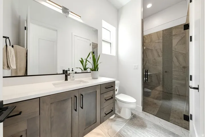 Contemporary bathroom featuring a spacious vanity with wood-finish cabinetry, a white countertop, and an undermount sink