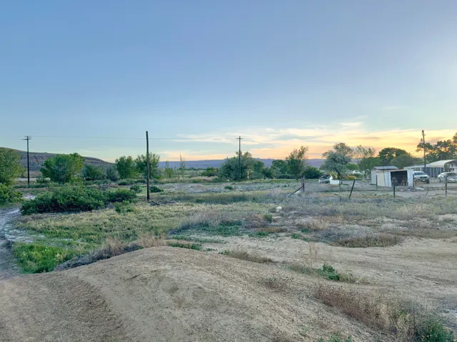 Expansive open land with varied vegetation, distant hills, and utility poles