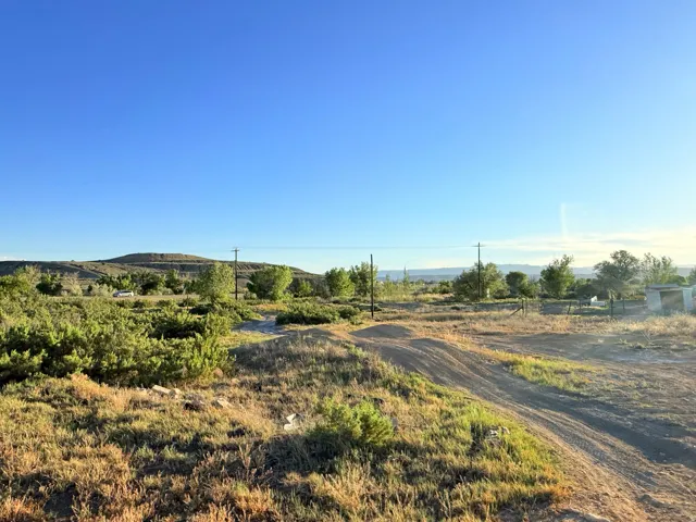 Expansive undeveloped land featuring natural vegetation, distant rolling hills, and a clear sky backdrop