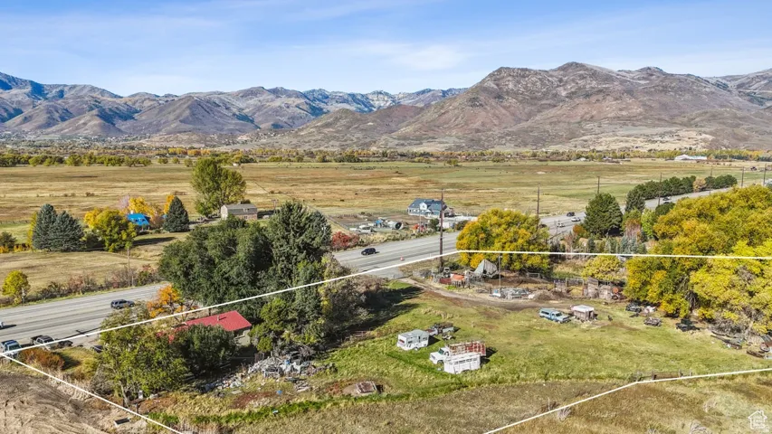 Expansive rural property featuring an open field, mature trees, and mountainous terrain in the background