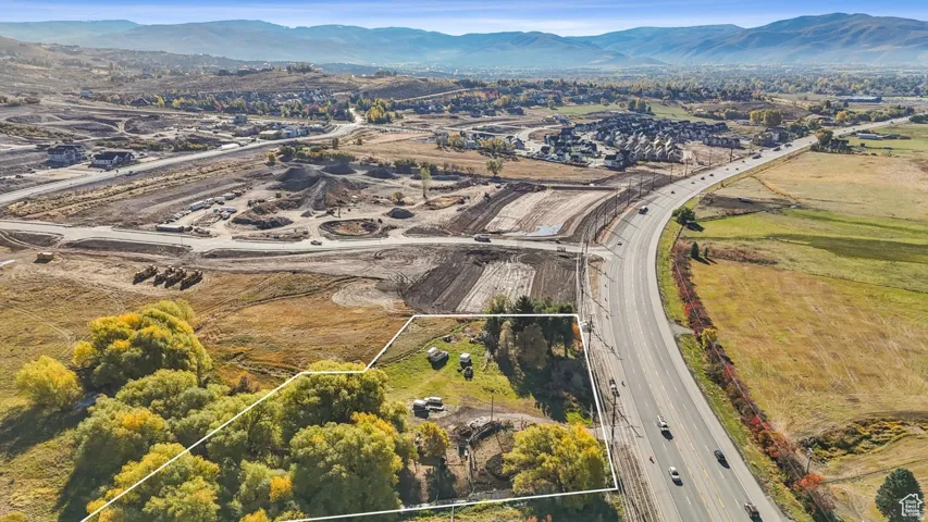 Expansive land parcel featuring mature foliage, a defined property boundary, and proximity to a multi-lane roadway