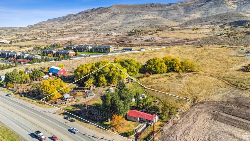 Expansive property with a red-roofed structure, highway frontage, and surrounding natural landscaping