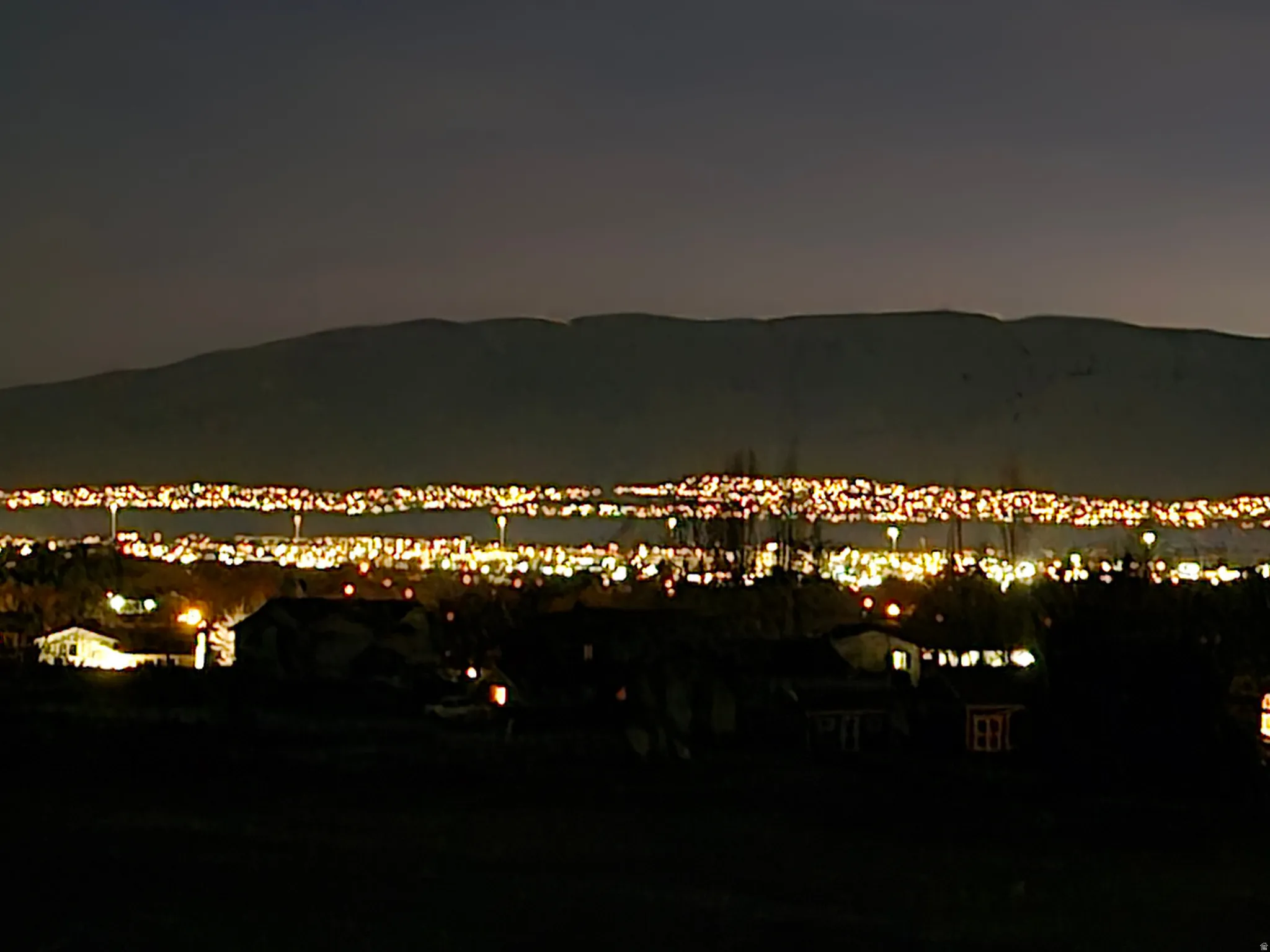 Panoramic city lights extending across the landscape with distant mountain ranges