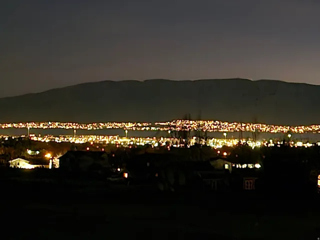 Panoramic city lights extending across the landscape with distant mountain ranges