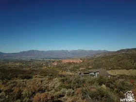 Elevated property featuring a multi-level structure with a dark roof and light-colored siding, surrounded by natural desert landscaping