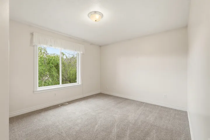 Bright room featuring a large window, neutral carpeting, white baseboards, and a semi-flush mount ceiling light fixture