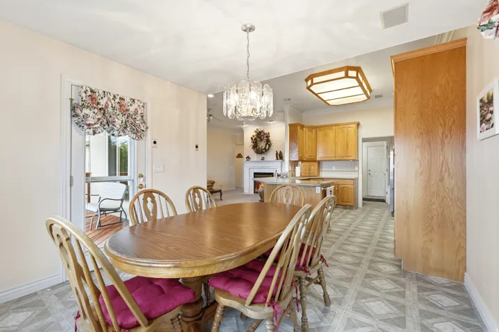 Dining area featuring a crystal chandelier, wood-finish flooring, and direct access to an outdoor patio with wood decking