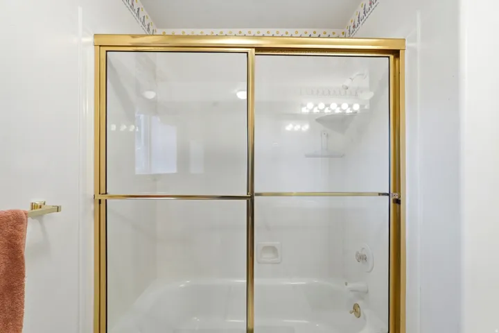 Bathtub with gold-finish sliding glass enclosure