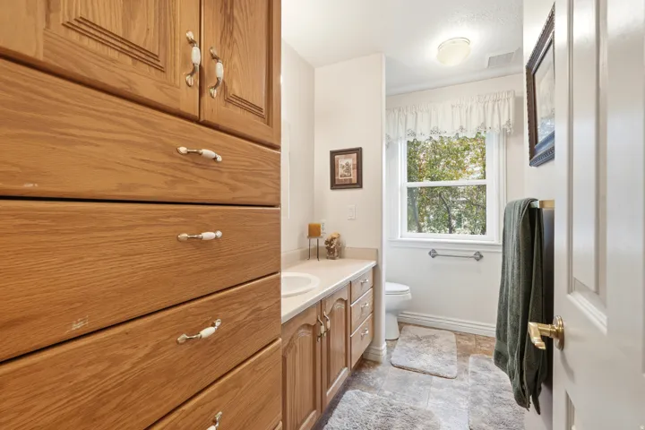 Bathroom featuring extensive wood-finish cabinetry, a window with a valance, tile flooring, and a vanity with an integrated sink