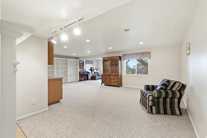 Spacious room featuring light-colored carpeting, recessed lighting, and a large window providing natural light