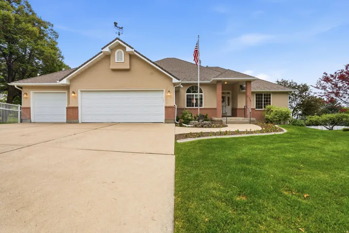Stucco exterior with brick-finish accents, a three-car garage, and a covered front entry