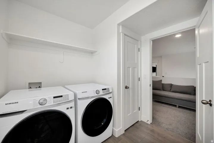 Dedicated laundry area featuring a built-in wall shelf and wood-finish flooring