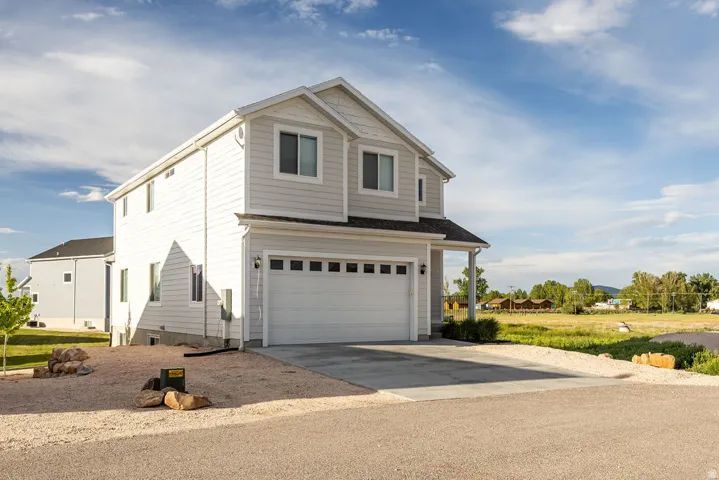 Two-story residence featuring light-colored siding, an attached two-car garage, and a covered porch entry