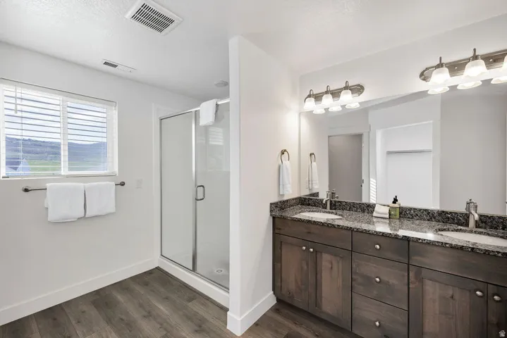Bathroom featuring a dual vanity with granite countertop, wood-finish cabinetry, and brushed nickel hardware