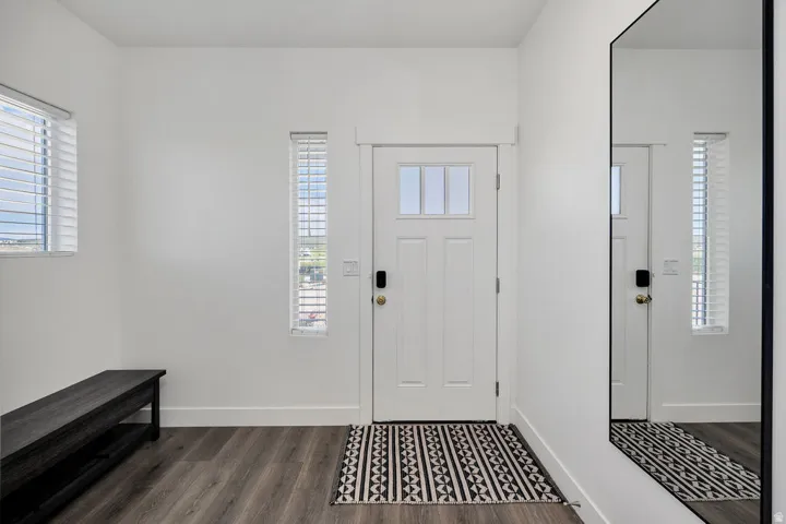 Entryway featuring a white paneled door with upper glass inserts, wood-finish flooring, and white walls