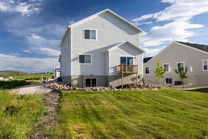 Light-colored siding exterior with a wood deck, sliding glass door access, and a walk-out basement