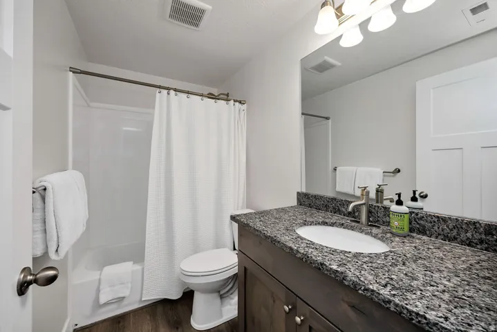 Bathroom featuring a dark wood vanity with a speckled countertop, an undermount sink, and a brushed nickel faucet