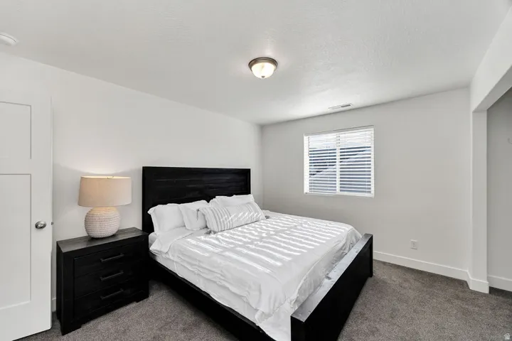 Bedroom featuring a single window with blinds, a white door, and a built-in overhead light fixture