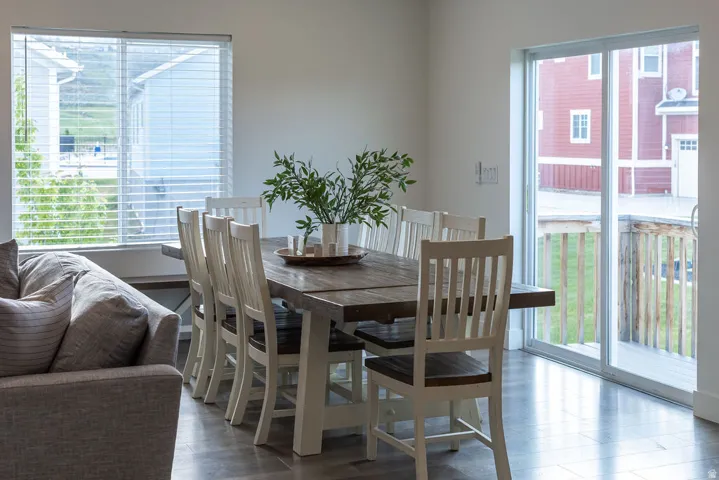 Spacious dining area featuring wood-finish flooring, a large window with blinds, and a sliding glass door providing exterior access