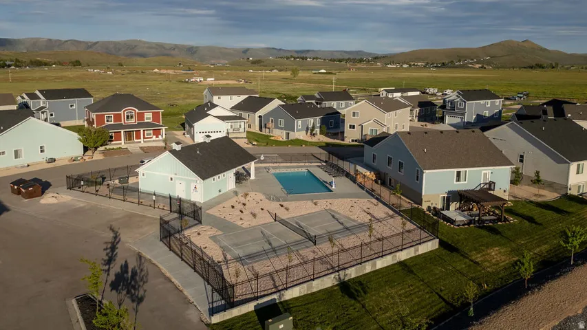 Community pool and clubhouse featuring a fenced perimeter, surrounding paved areas, and manicured landscaping