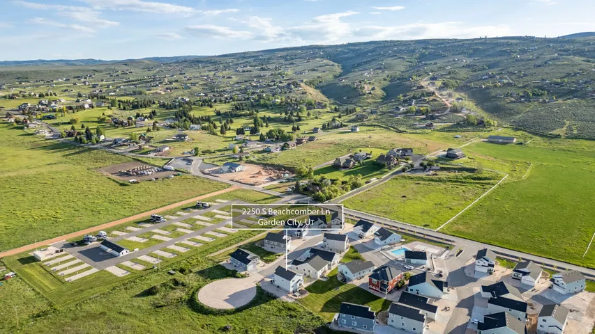 Expansive aerial perspective showcasing a residential community with a manicured green space, a community pool, and a structured RV parking area