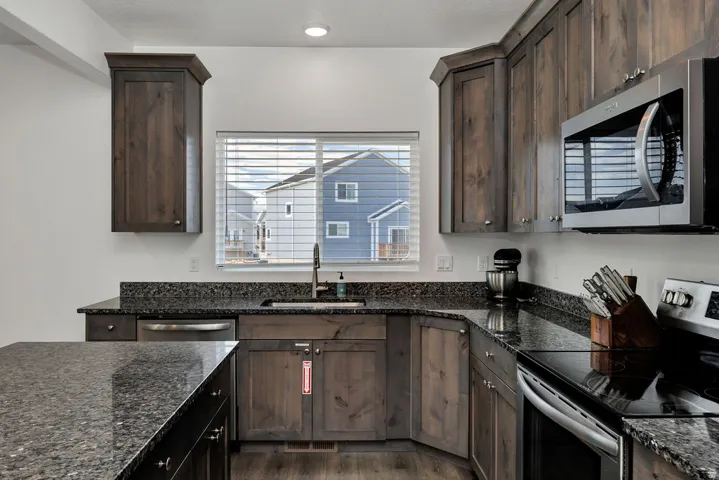 Kitchen featuring dark wood-finish cabinetry, speckled countertops, and stainless steel appliances