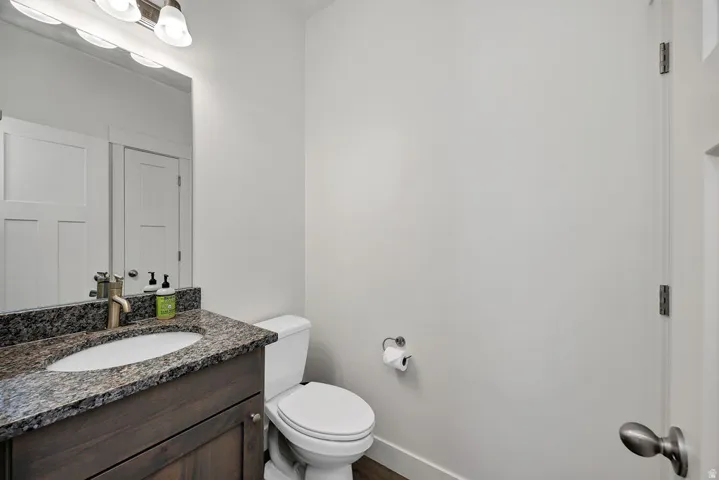Bathroom featuring a dark wood-finish vanity with a granite countertop, undermount sink, and brushed brass faucet