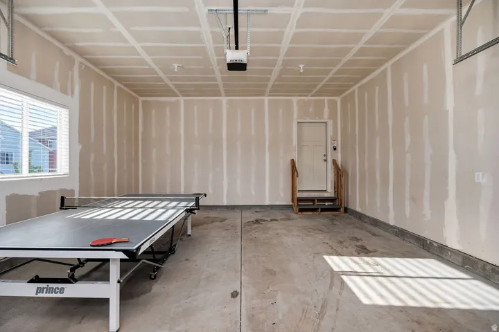 Spacious garage featuring a concrete floor, high ceilings, and a window with blinds
