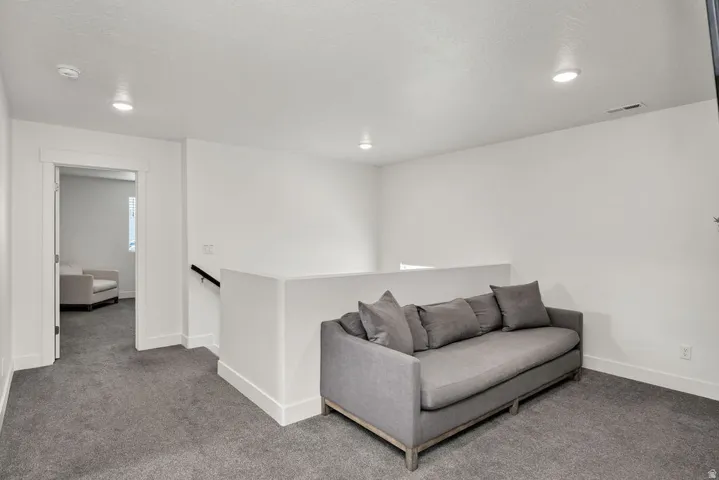 Carpeted landing with white walls, recessed lighting, and a white half-wall balcony railing