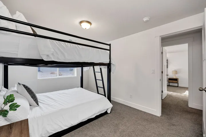 Carpeted room featuring a white baseboard, a window with horizontal blinds, and a standard white door leading to another room