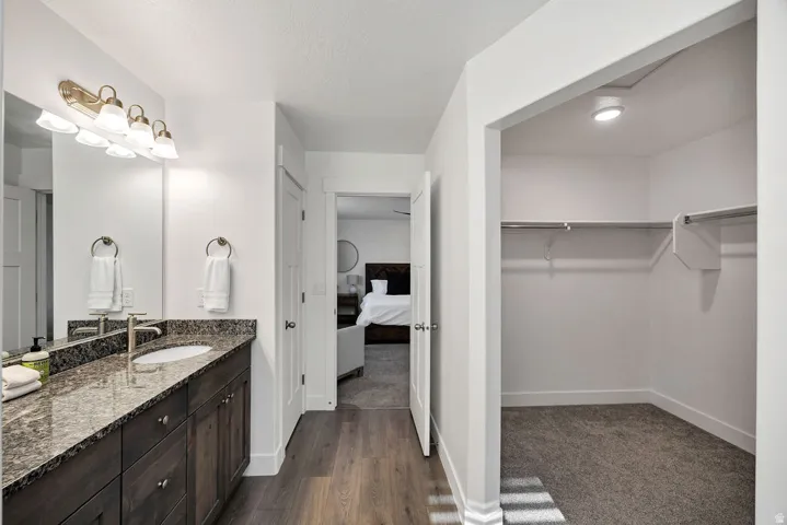 Bathroom vanity with granite-style countertop, undermount sink, and dark wood-finish cabinetry