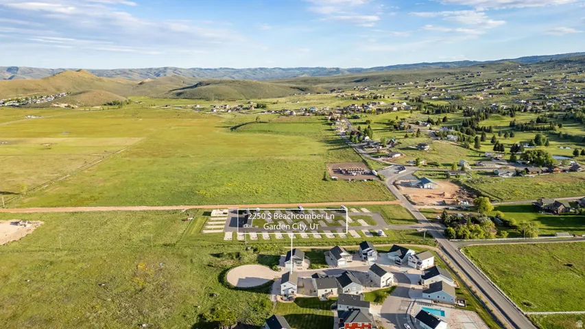Expansive aerial of a residential development with surrounding green spaces and distant hills
